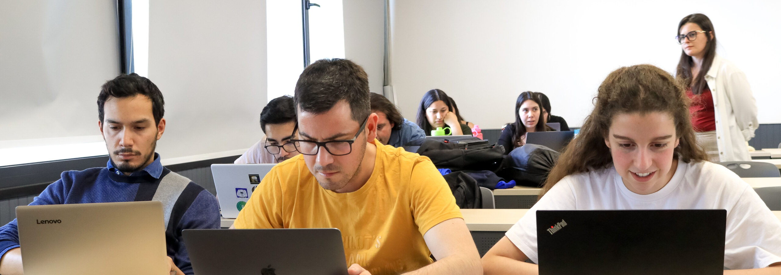 Estudiantes en sala de clase utilizando notebook